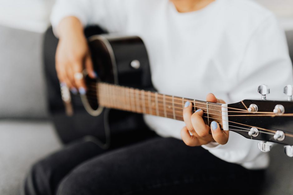 A beginner practicing guitar next to an open notebook.